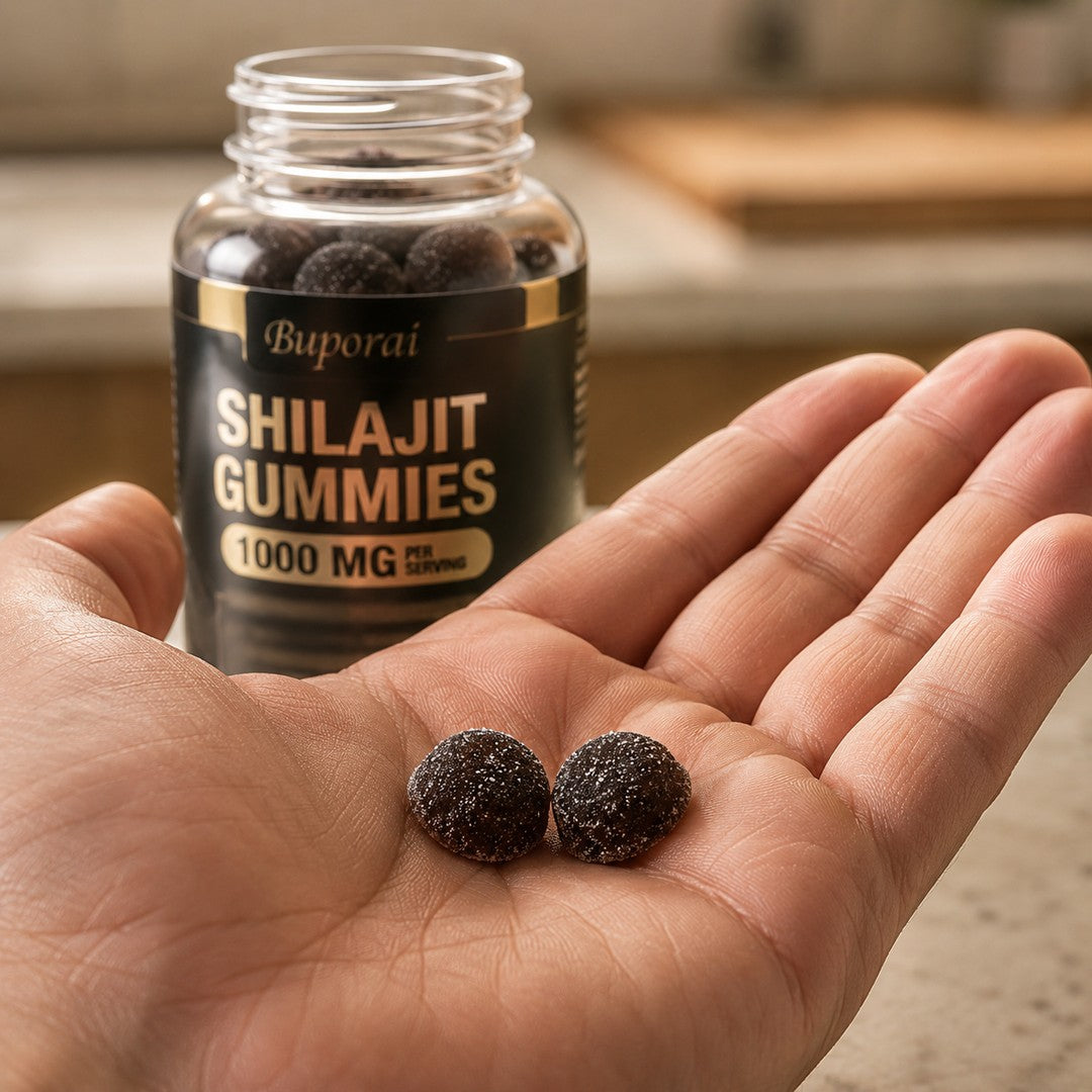 Mano sosteniendo las dos gomitas oscuras de shilajit junto al frasco abierto